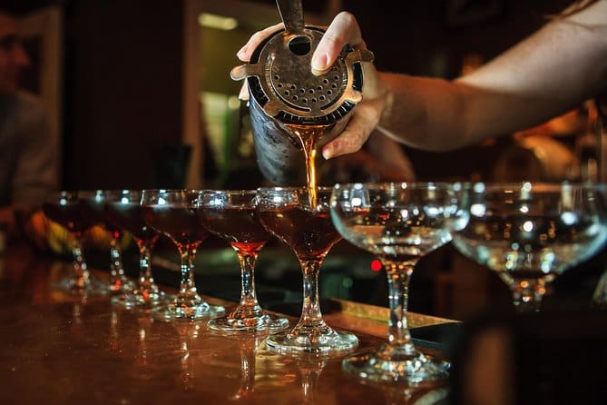 A person pouring wine into glasses on top of a table.