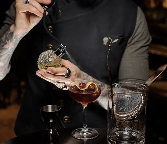 A person holding a donut in front of a glass.