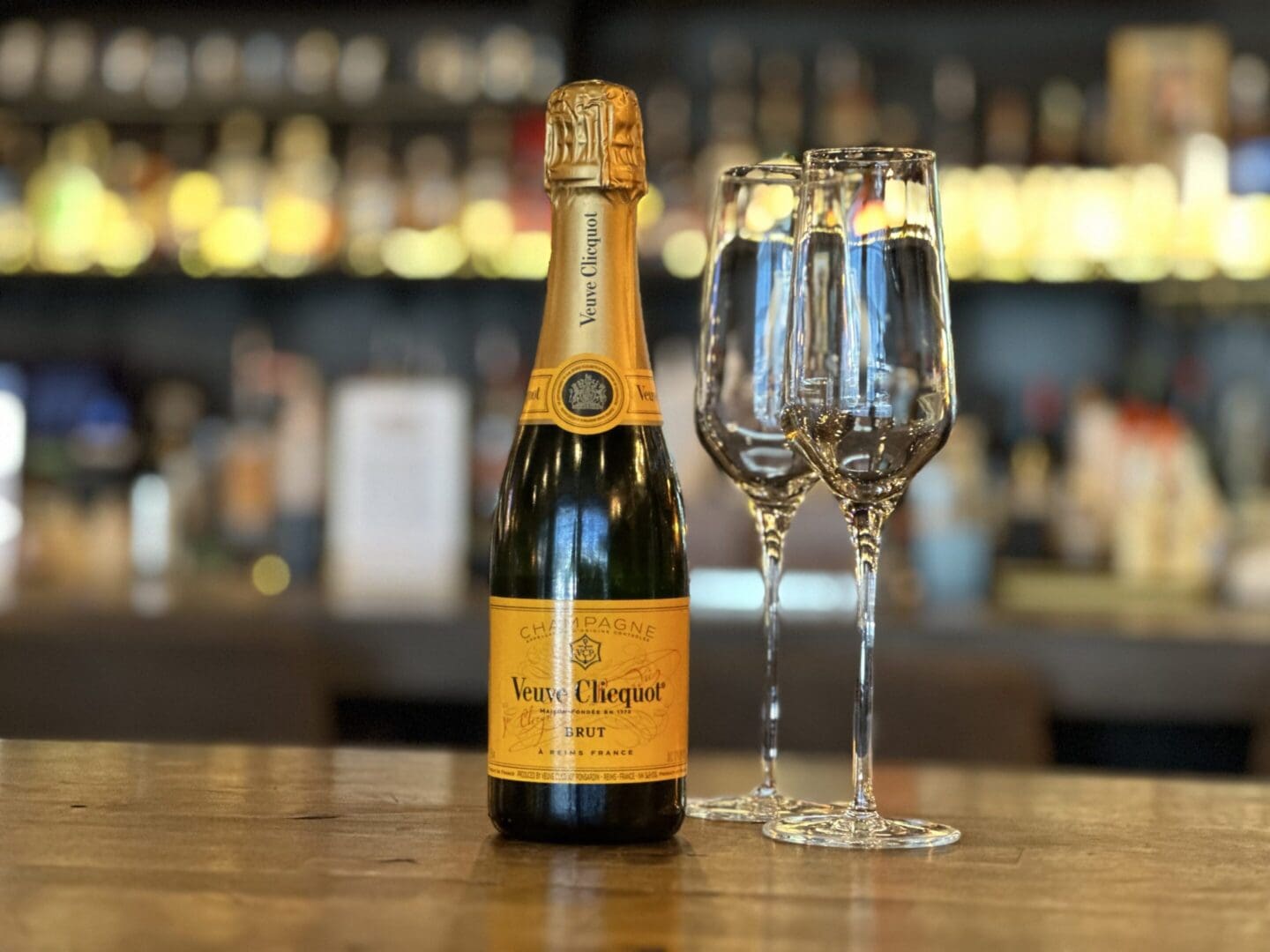 A bottle of champagne and two wine glasses on a table.