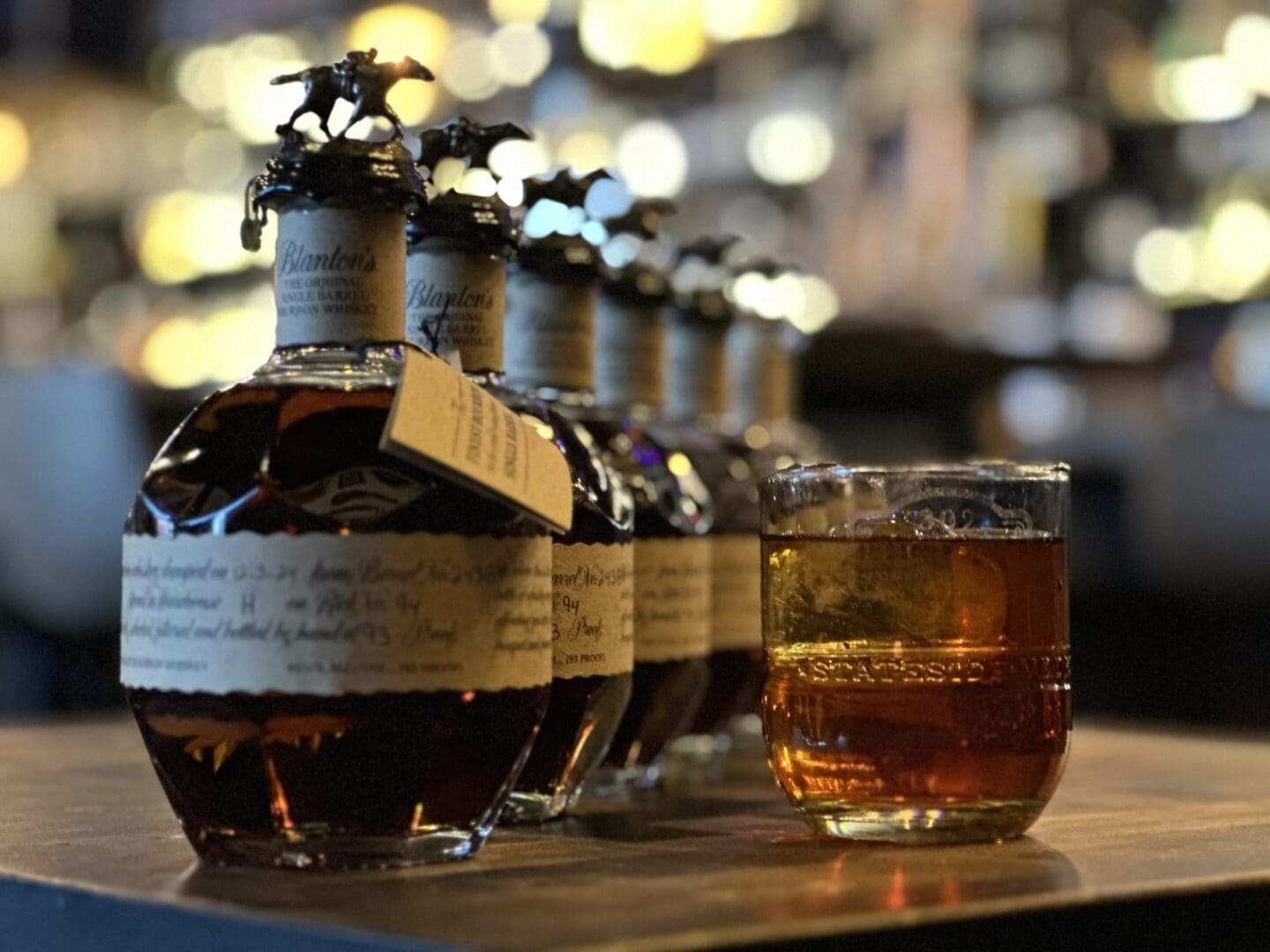 A glass of whiskey and some bottles on the table