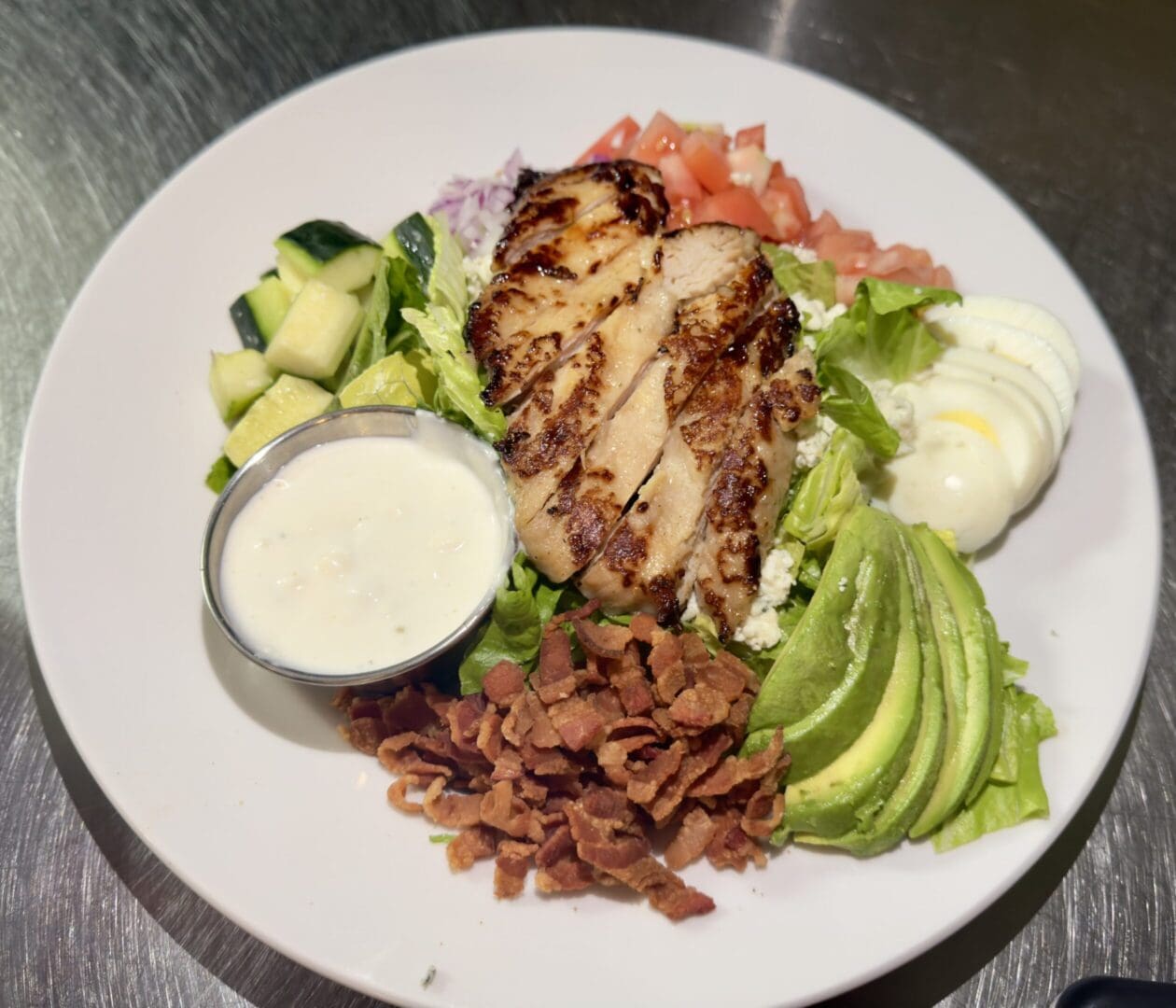 A plate of food with chicken, avocado and other vegetables.