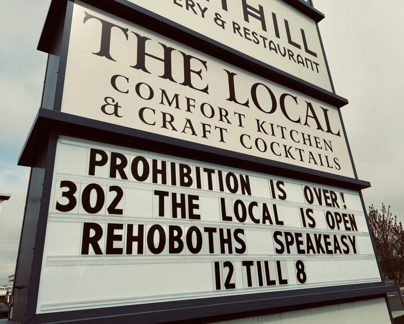 A sign that says the local, the thil and the rehoboth speakeasy.