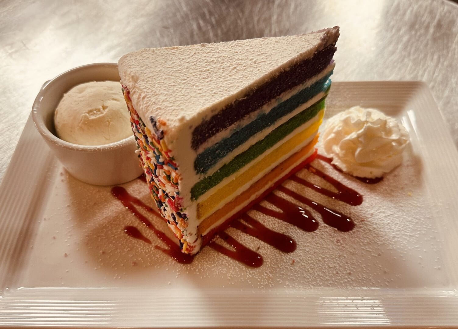 A slice of cake with frosting and chocolate sauce.