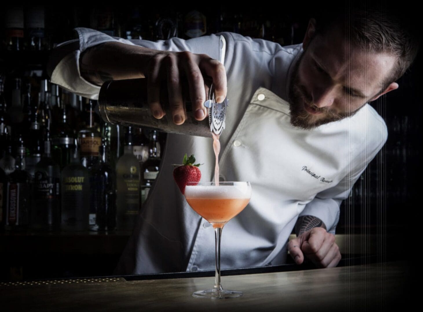 A man pouring liquid into a glass with an orange drink.