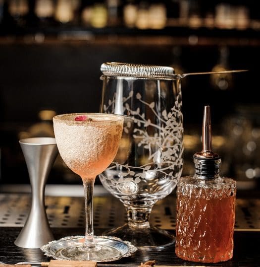 A table with two glasses and a bottle of alcohol.