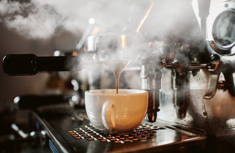 A cup of coffee is being poured into the steam.