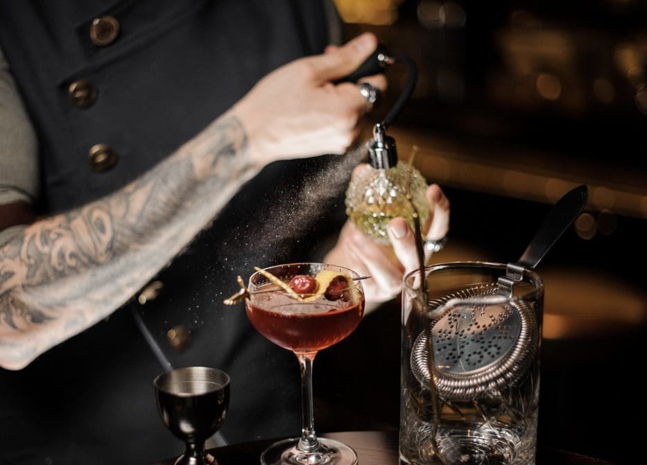 A person holding a phone and drinking a cocktail.