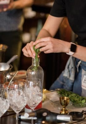 A person is putting some green plants in a bottle.