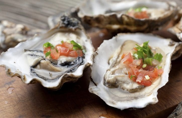 A close up of some oysters with tomatoes on them