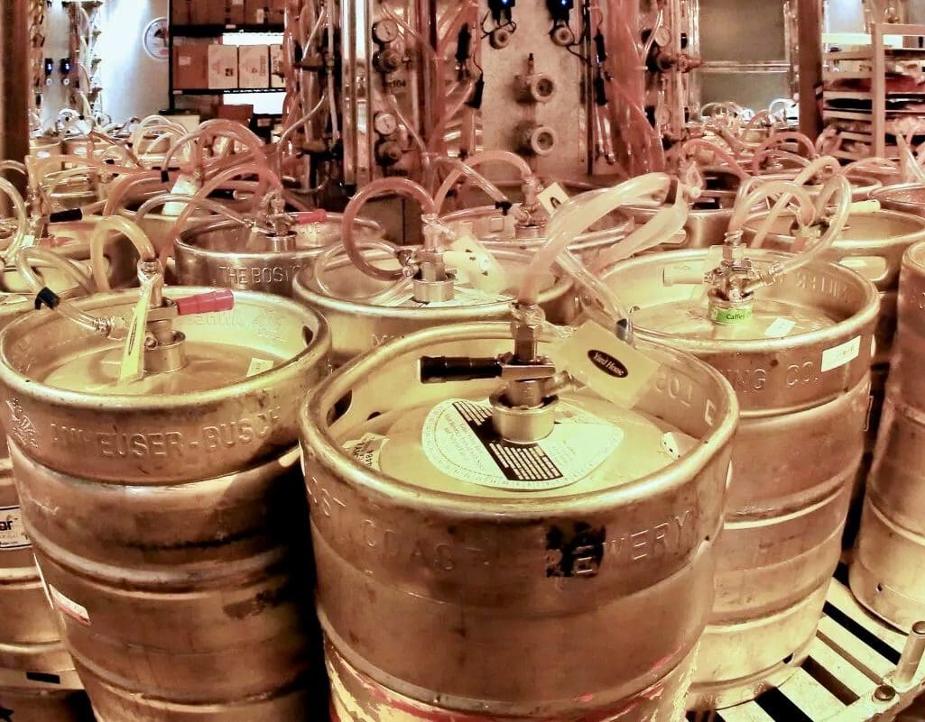 A bunch of beer kegs are lined up