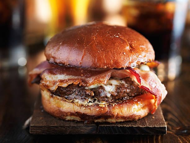 A hamburger with bacon on top of it.