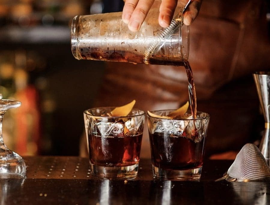 A person pouring some liquid into two glasses.