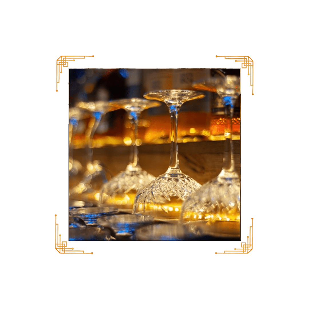 A picture of some wine glasses in front of bottles.